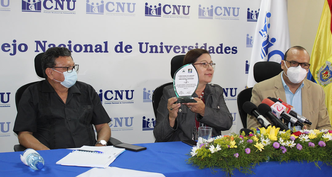 Presidenta del CNU porta reconocimiento que esta institución recibió.