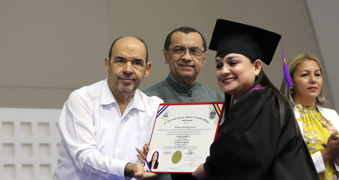 Graduada recibe título de manos del vicerrector general de la UNAN-Managua.