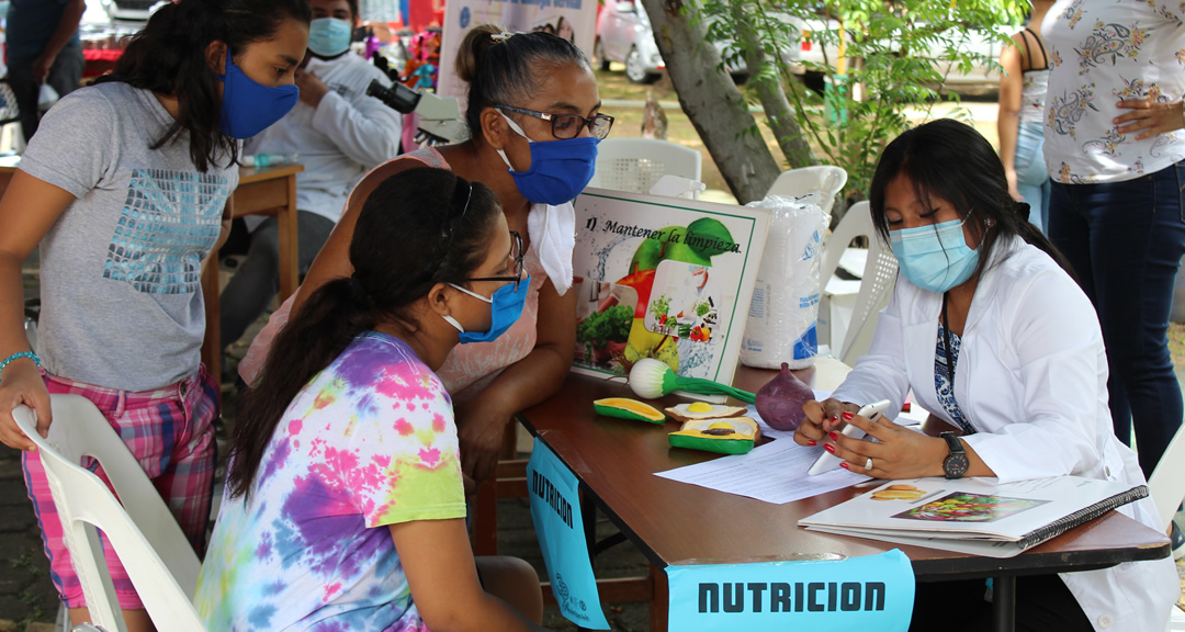 Familias recibiendo orientación nutricional en la feria.