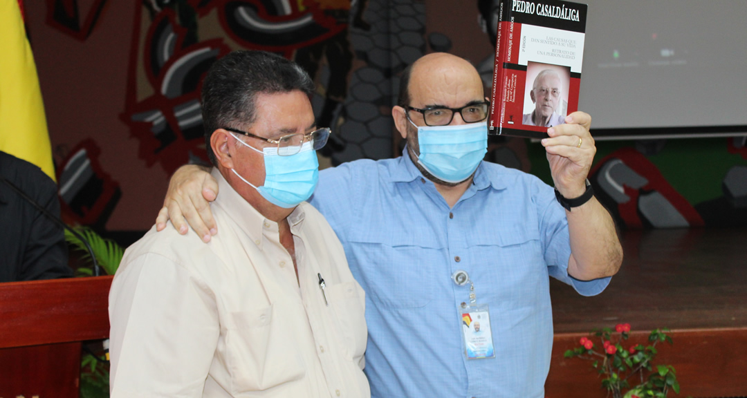 El Dr. Luis Alfredo Lobato, Secretario General de la UNAN-Managua y Coordinador del Centro de Estudio del Desarrollo Miguel d’Escoto Brockmann recibe de manos del Sr. Juan Manuel Gutiérrez, familiar del padre Miguel, el donativo de un libro sobre la vida del Obispo Pedro Casaldáliga.